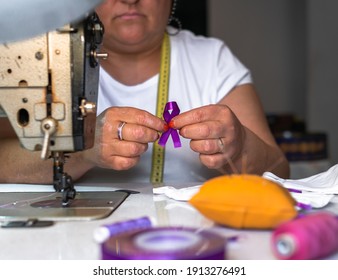 Working Woman, Woman Sewing Purple Ribbon On Face Masks. 