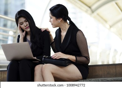 Working Woman Sitting With Friend On The Stair Case . Empathy Concept. The Woman Hand Touch Friend Shoulder For Empathy.The Working Woman Worry About Work And Feeling Sick With Laptop Outdoor .