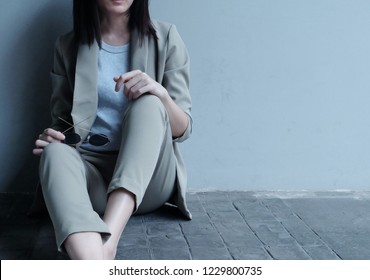 Working Woman Sitting On The Concrete Floor And Lean Against The Grey Wall For Resting After Long Meeting All Day