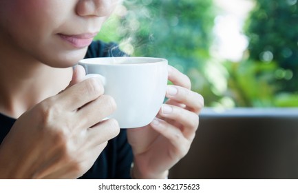 Working women are drinking hot coffee from a white cup.