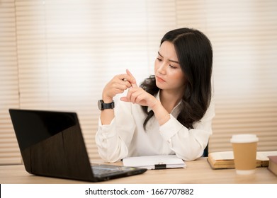 Working women holding finger in pain on the desk
