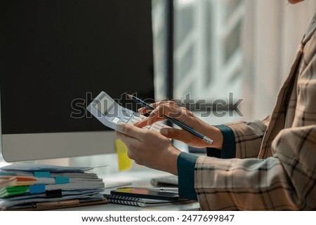 working in workplace on the desk with computer, female employee is looking on document, en entrepreneur is trying so hard to build startup company, finance department