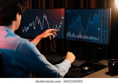 Working young business trader pointing on market stock graph data planning in real time monitor with back side view at neon modern office. Concept of analyzing dynamic financial exchange rate. Gusher.
