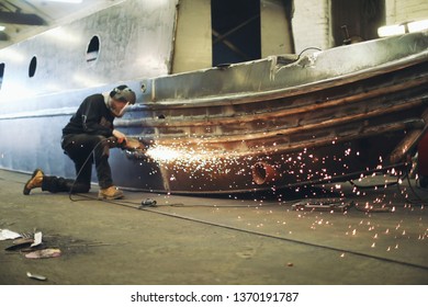 Workman angle grinding on boat
