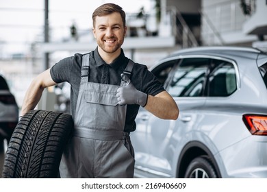 Workman At Car Repair Shop Changing Tires