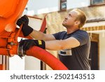 workman connects a suction hose to a sewage tanker truck. Septic tank maintenance. Sewer pumping machine. Septic truck. Pumping wastewater from a septic tank. Septic tank maintenance