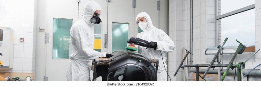 Workman In Hazmat Suit Holding Car Part Near Colleague With Polisher In Service, Banner