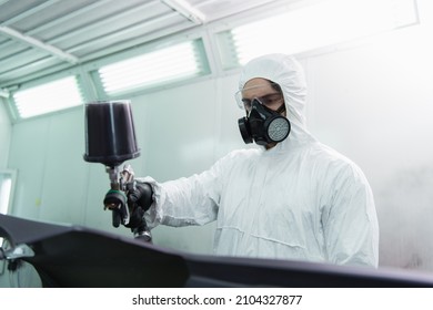 Workman In Hazmat Suit And Respirator Coloring Blurred Car Part In Service