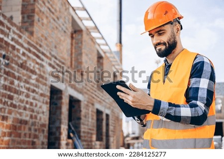 Workman making notes bu the building object