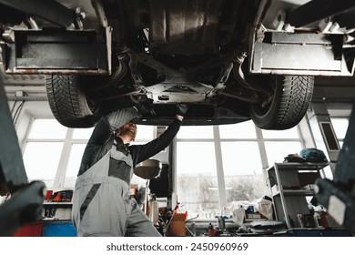 Workman mechanic working under car in auto repair shop - Powered by Shutterstock