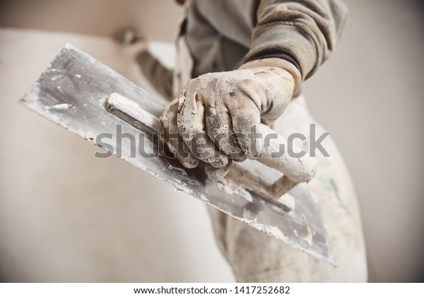 Workman\
plastering gypsum walls inside the\
house.