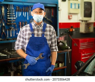 Workman In Protective Mask Standing Near Car At Auto Repair Shop