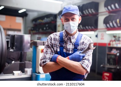 Workman In Protective Mask Standing Near Car At Auto Repair Shop