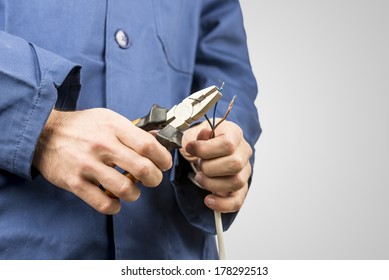 Workman Repairing An Electrical Cable With A Pair Of Pliers. On Grey Background With Copyspace.