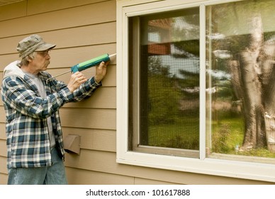 Workman Sealing An Exterior Window With Caulk To Reduce Air Infiltration