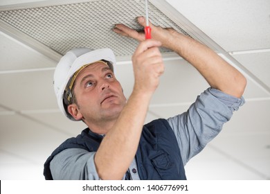 Workman Securing Screws On Ceiling Vent