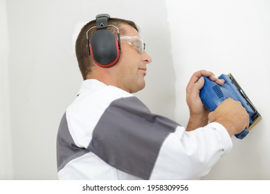 workman using cordless sander on interior wall