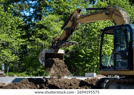 Workman using excavator, heavy construction equipment, to remove dirt to dig new house foundation, earthworks
