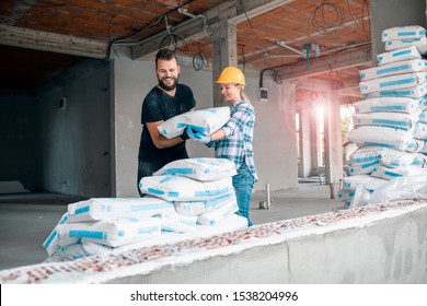 Workman and woman civil engineer carrying cement bag on construction site .Female and man working together in building new house