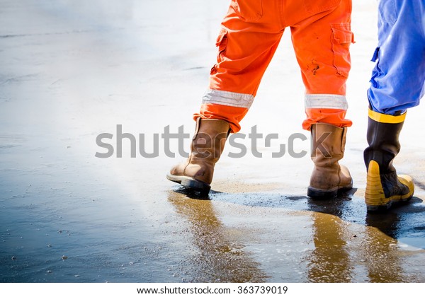 Workmans boots in oil and gas industrial, safety\
boos for firefighter worker petroleum process, Worker walk with\
safety shoes on wet\
floor.