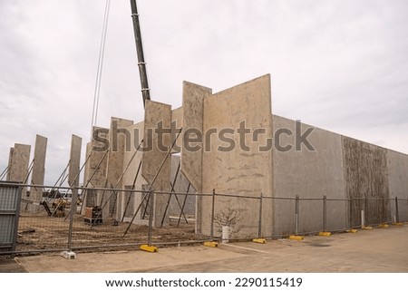 Workmen completing the foundations of a tilt-up warehouse being constructed of prefabricated concrete panels.	