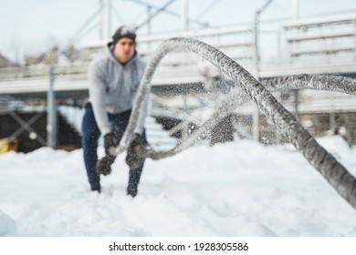 Workout With A Battle Ropes. Young Athlete During His Outdoor Training During Snowy Winter Day. Camera Focus On The Front Rope.