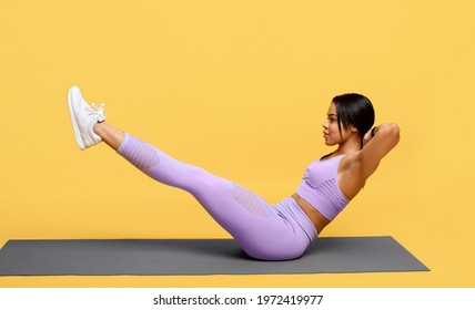 Workout concept. Sporty african american woman doing abs exercise with raised legs, training on mat on yellow studio background, side view. Full length, banner. Sport and fitness concept - Powered by Shutterstock