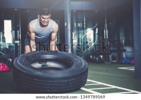 workout concept; young man practicing workout in class ; feeling commitment and patience to weight lifting with big tires