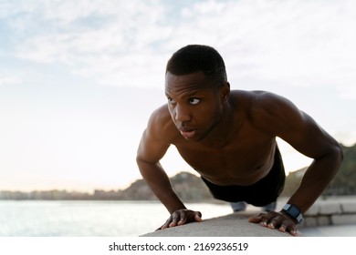 Workout exercise. Full length view of healthy active man with fit muscular body doing push ups exercises. Sporty athletic male exercising at beach, training outdoor. Sports and fitness concept 