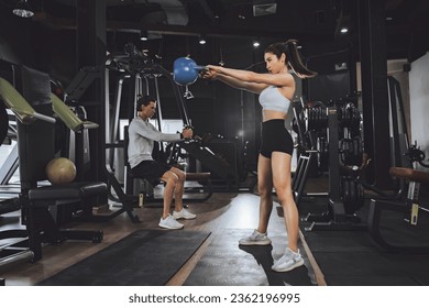 Workout, Fitness workout in gym with trainer assisted in training, Fitness concept, Fit asian woman, Young white man and asian girl exercising in the gym. - Powered by Shutterstock