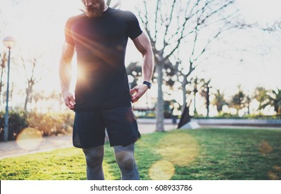 Workout lifestyle concept.Young man preparing muscles before training.Muscular athlete exercising crossfit outside in sunny park. Blurred background