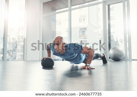 Workout, man and push up in gym for fitness, health and wellness, athlete and training. Exercise, strong and bodybuilder in sport club for body endurance, performance and medicine ball for muscle