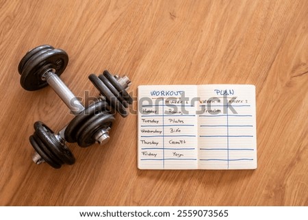 Workout Plan In Notebook With Daily And Weekly Exercises, Including Dumbbells