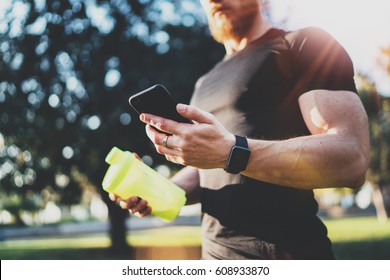 Workout smart fitness concept.Young Muscular athlete checking training programm on smartphone application after perfect crossfit outdoor session at sunny morning.Blurred background - Powered by Shutterstock