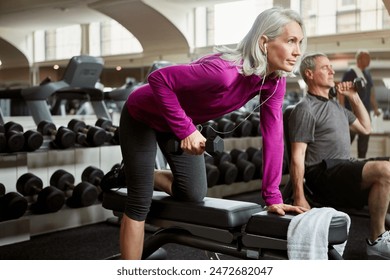 Workout, weights and senior woman in gym for fitness, training and cardio exercise listen to music. Retirement, sports and person with dumbbells for wellness, muscle strength and mobility for health - Powered by Shutterstock