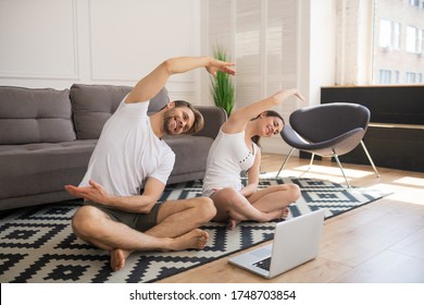 Workout. Young couple in white tshirts leaning while having online workout together at home