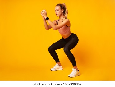 Workout. Young Woman Doing Deep Squat Exercise Over Yellow Studio Background. Copy Space