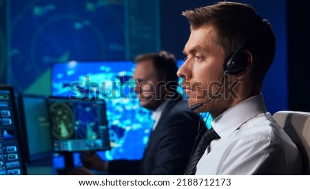 Workplace of the air traffic controllers in the control tower. Team of professional aircraft control officers works using radar, computer navigation and digital maps. Aviation concept.