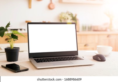 A workplace in a bright kitchen during quarantine. Laptop with place for text. Telework. freelance. flowerpot, phone and cup on the table. sunlight - Powered by Shutterstock