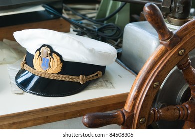 Workplace of the captain. Still-life on marine subject matter with a peak-cap and a steering wheel