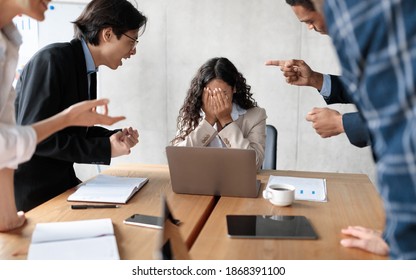 Workplace Conflict And Bullying. Aggressive Coworkers Yelling At Victimized Businesswoman Sitting At Desk In Modern Office. Corporate Communication Problem, Quarrels And Bad Attitude At Work