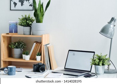 Workplace of contemporary stock photographer with photocamera, laptop, drink in mug and table lamp in office - Powered by Shutterstock