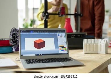 Workplace Of Creative Engineer Or Designer With Laptop And Picture Of New 3d Model On Display On Background Of Two Employees