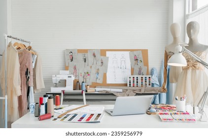 Workplace of designer dressmaker with dummy mannequin, sewing machine, laptop, thread, sketches, and equipment other in the fashion design studio office. Small business freelance startup concept. - Powered by Shutterstock