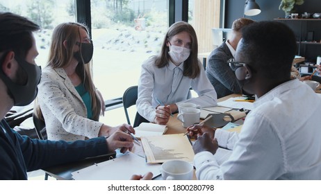 Workplace With Epidemic Safety Measures. Young Multiethnic Business Colleagues Work At Office Table Meeting, Wear Masks.