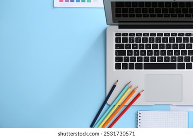 Workplace of graphic designer with laptop, colorful pencils and notebook on blue background - Powered by Shutterstock