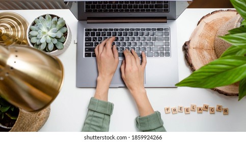 Workplace at home. Laptop, plants and wooden lettering: "Freelance" on a white table. Start of the working day in quarantine. The concept of human resource management, recruitment and recruitment.