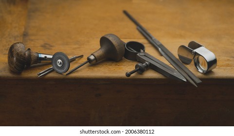 Workplace of a jeweler. Tools and equipment for jewelry work on an antique wooden desktop. Jeweller, engraver at work on jewelry made of diamonds and gold