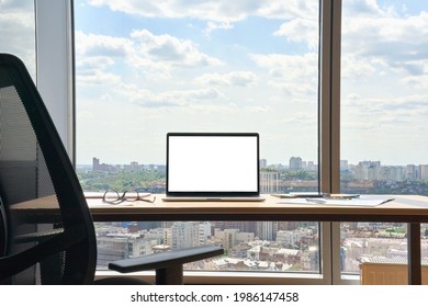 Workplace With Laptop On Desk With Blank Empty Mockup Screen For Advertising Standing In Modern Contemporary Office On High Floor With Panoramic Big City Urban View. No People. Business Concept.