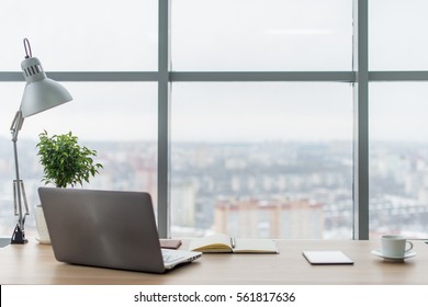 Рабочее место с ноутбуком Удобный рабочий стол в офисных окнах и вид на город.